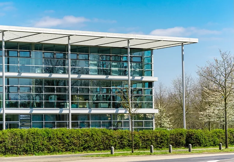 "Modern commercial office building with large glass windows and surrounding landscaping, representative of facilities that rely on booster and HVAC pump systems for water pressure and climate control.