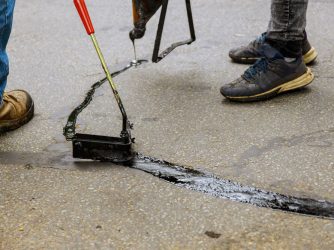 Construction workers spot-applying asphalt to seal cracks, using equipment sourced by Arroyo Process Equipment